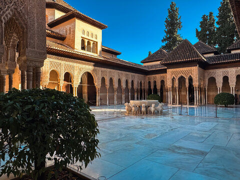 Granada, Spain - 30 October 2025: View of the Alhambra with its iconic Court of the Lions, featuring intricate Moorish arches, marble flooring, and a clear blue sky.