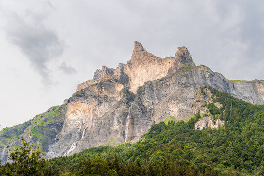 View of the Cirque du Fer a Cheval with its dramatic limestone cliffs, cascading waterfalls, and lush green forest slopes in Sixt-Fer-a-Cheval, Auvergne-Rhone-Alpes, France.