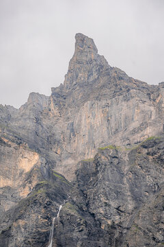 View of the dramatic limestone peak of Cirque du Fer a Cheval with a cascading waterfall on the rugged cliff face in Sixt-Fer-a-Cheval, Auvergne-Rhone-Alpes, France.