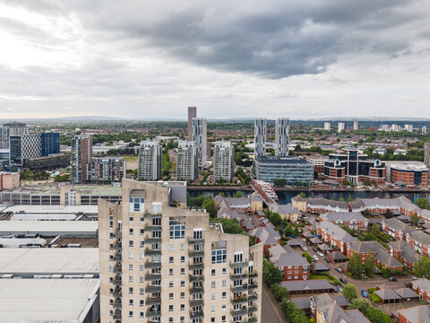 Aerial view of the Manchester skyline featuring modern high-rise apartment buildings, residential areas, and commercial developments along the waterfront in Manchester, England, United Kingdom.