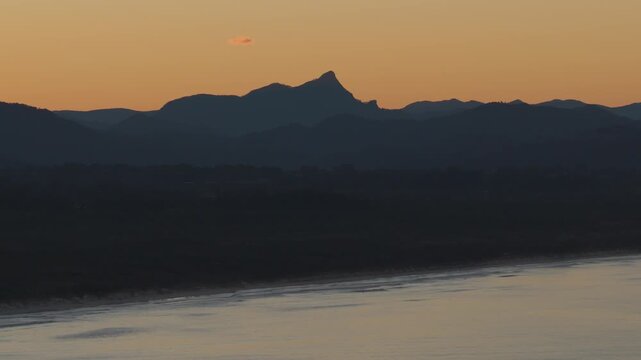 Aerial view of the coastline at Byron Bay during golden hour with Mount Warning silhouetted against the sky in Byron Bay, New South Wales, Australia.