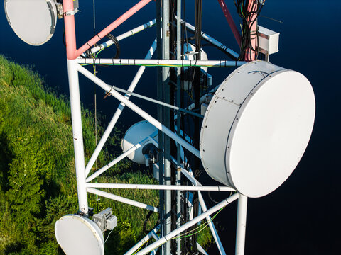 Aerial view of a telecommunications tower with multiple satellite dishes situated along the banks of the Bullupe River in Riga, Latvia.