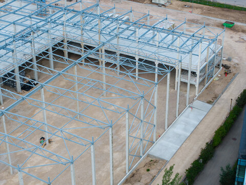Aerial view of the steel frame structure of a building under construction with concrete pillars and gravel ground in Riga, Latvia.
