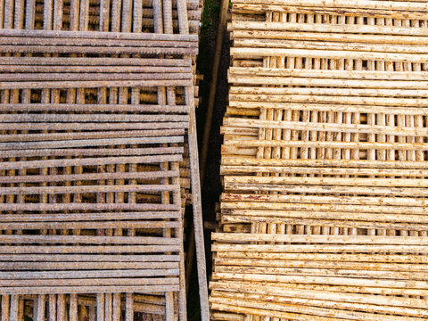 Aerial view of stacked metal rebar and wooden poles arranged in parallel rows at a construction site in Brankas, Jelgava Municipality, Latvia.
