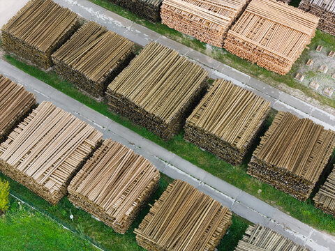 Aerial view of stacked timber logs in a lumber yard with rows of wood piles on grass Jelgava Municipality, Latvia.