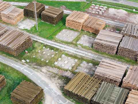Aerial view of stacked lumber and timber in a storage yard with concrete foundations and pathways in Jelgava Municipality, Latvia.