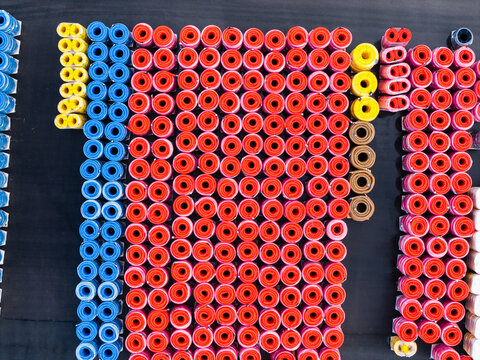 Aerial view of organized stacks of colorful plastic pipes in red, blue, yellow, and brown stored in a manufacturing yard in Jelgava, Latvia.