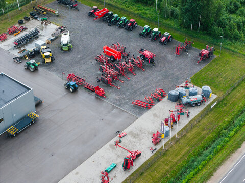 Brankas, Jelgava Municipality, Latvia - 05 July 2026: Aerial view of an agricultural machinery sales center featuring rows of tractors, farm equipment, and storage tanks on a paved lot.