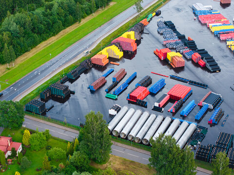 Aerial view of a polymer pipe manufacturing facility with rows of colorful plastic pipes, large cylindrical tanks, and industrial storage areas in Jelgava, Latvia.