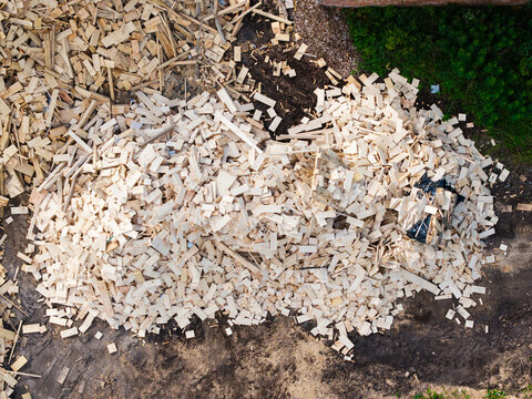 Aerial view of a large pile of wood scraps and lumber offcuts on the dark soil ground, Jelgava Municipality, Latvia.