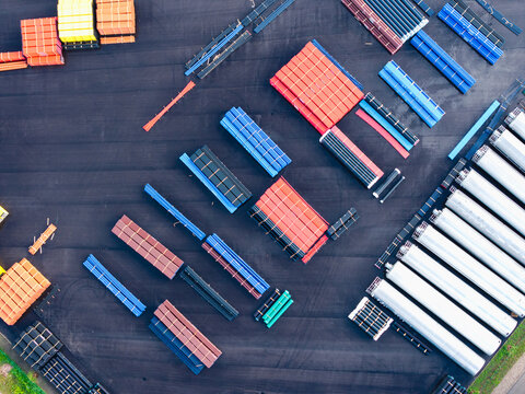 Aerial view of an industrial storage yard filled with stacks of colorful polymer pipes and large plastic conduits in Jelgava, Latvia.