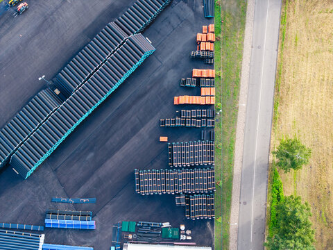 Aerial view of stacks of black and orange polymer pipes arranged in rows at a manufacturing facility in Jelgava, Latvia.