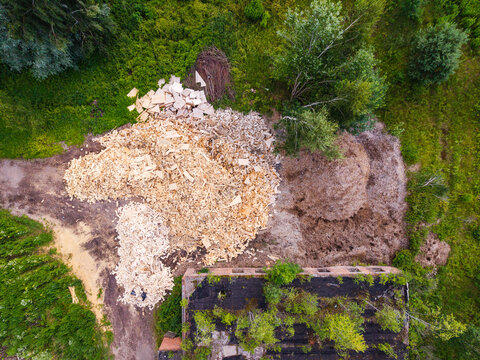 Aerial view of wood chips and sawdust piles near an overgrown building in Jelgava Municipality, Latvia.