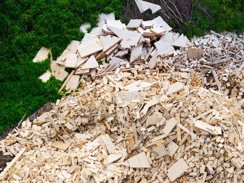 Aerial view of a large pile of wood scraps and lumber debris situated near a green forest area in Jelgava Municipality, Latvia.