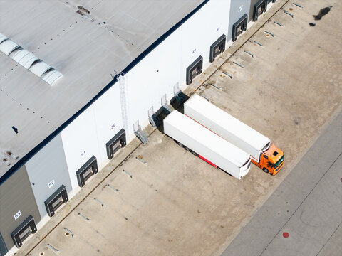Aerial view of a modern logistics and industrial park with loading docks and semi-trucks parked at the facility in Lielvarzi, Kekava Municipality, Latvia.