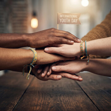 Diverse group of people stacking hands in unity celebrating international youth day and team.