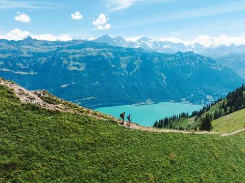 Aerial view of hikers walking along the Hardergrat mountain ridge trail with Lake Brienz in the background, surrounded by the Emmental Alps in Habkern, Bern, Switzerland.