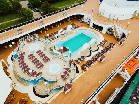 Riga, Latvia - 19 May 2022: Aerial view of the cruise ship deck featuring a swimming pool, hot tubs, and lounge chairs.