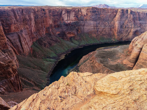 Aerial view of Horseshoe Bend with its dramatic red sandstone cliffs and the winding Colorado River flowing through the deep canyon in Coconino County, Arizona, United States.