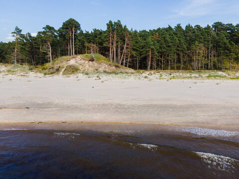 Aerial view of a sandy beach with dunes and a dense pine forest in the background in Bernati, South Kurzeme Municip, Latvia.