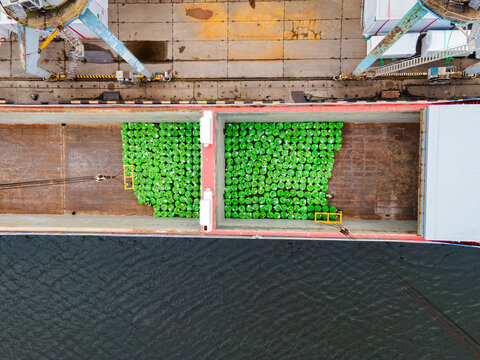 Aerial view of cargo ship hold filled with green bags of mineral fertilizers being loaded at the port in Riga, Latvia.