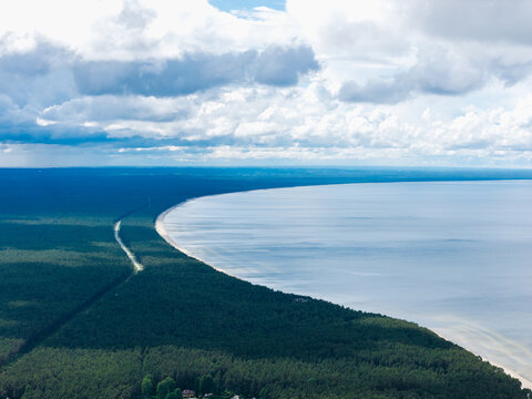 Aerial view of the coastline at Ragaciems with dense pine forests bordering the sandy beach and the calm waters of the Gulf of Riga in Ragaciems, Tukums Municipality, Latvia.