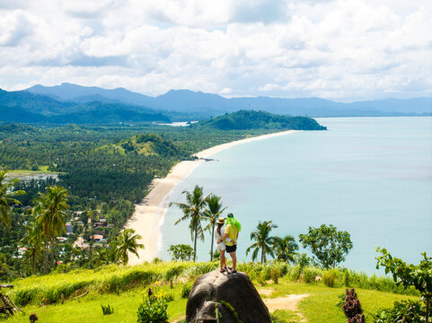 Aerial view of a couple standing on a rock at Ningning Viewpoint overlooking the coastline with Erawan Beach, Boong Beach, and Nagtulay Beach in San Vicente, Mimaropa, Philippines.