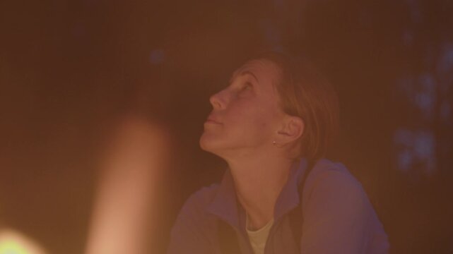 Young woman sits in front of the bonfire burning in the wild