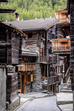 View of traditional wooden houses with intricate balconies and stone foundations in the historic village of Zermatt, Valais, Switzerland.