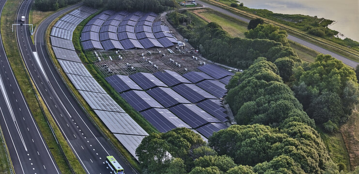 Den Oever, Netherlands - 19 June 2026: Aerial view of the solar farm under construction on the Highway A7 embankment, part of the Afsluitdijk project, with solar panels and trees.