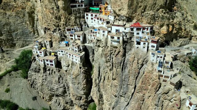 Aerial view of Phukthal Gompa monastery built into a steep cliffside with white buildings and rocky terrain in Phugtal, Himachal Pradesh, India.