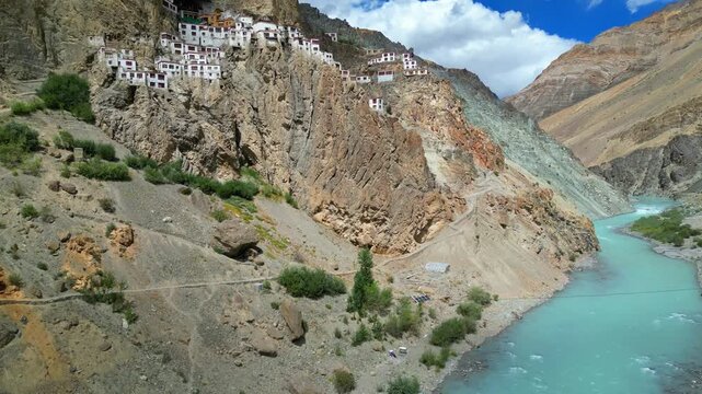 Aerial view of Phukthal Gompa monastery perched on a rocky cliff above the turquoise Lungnak River in the Zanskar region, Phugtal, Himachal Pradesh, India.