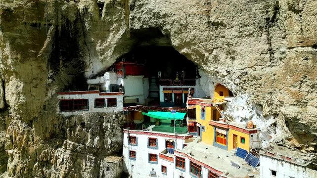Aerial view of Phukthal Gompa monastery built into a cliffside cave with white buildings and rocky surroundings in Phugtal, Himachal Pradesh, India.