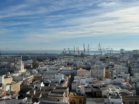 View of the historic city of Cadiz with its characteristic white rooftops, the bay, and the Constitution of 1812 Bridge in the distance in Cadiz, Andalusia, Spain.