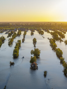 Aerial view of Scheendijk featuring small islands with houses and boats surrounded by calm water during golden hour in Breukelen, Utrecht, Netherlands.