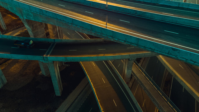 Aerial view of the multi-level Pokuase Interchange with concrete flyovers, road markings, and a vehicle driving at night in Ga North Municipal, Greater Accra Region, Ghana.