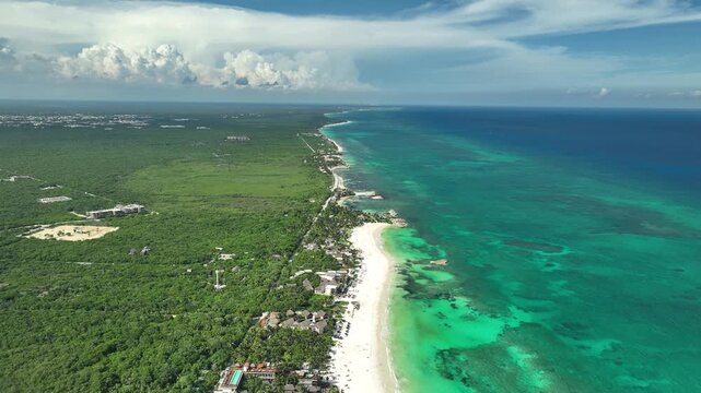 Aerial view of the turquoise Caribbean Sea, white sand beach, and lush jungle vegetation along the coast of Tulum, Quintana Roo, Mexico.