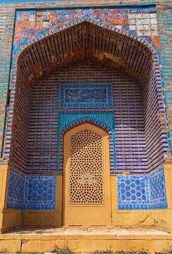 View of the intricate blue tilework and geometric patterns on the arched entrance of a historic tomb at the Makli Necropolis in Thatta, Sindh, Pakistan.