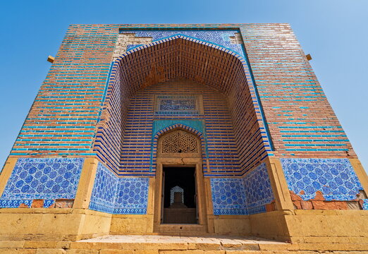 View of the historic Makli Necropolis featuring intricate blue tile work and brick architecture under a clear sky in Thatta, Sindh, Pakistan.
