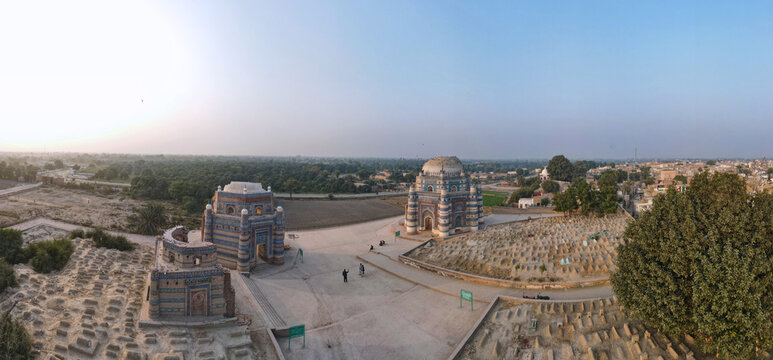 Aerial view of the historic blue-tiled shrines and tombs surrounded by an ancient cemetery and arid landscape in Uch Sharif, Punjab, Pakistan.