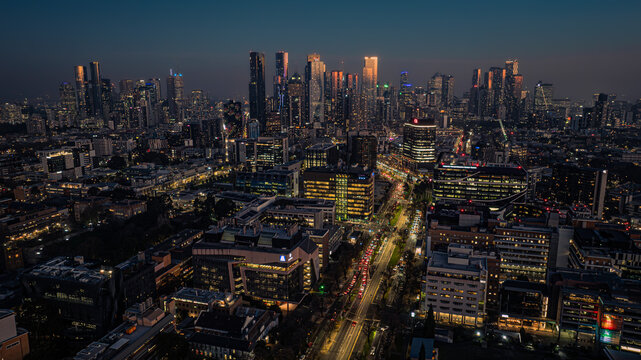 Aerial view of the Melbourne skyline at dusk with illuminated skyscrapers, busy city roads, and urban architecture in Parkville, Victoria, Australia.