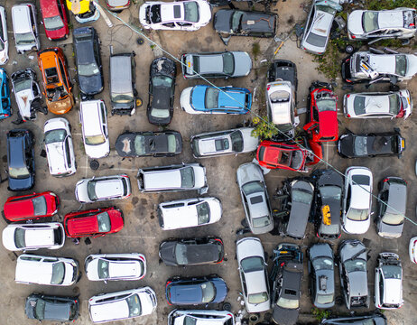 Aerial view of a car junk yard with many damaged and abandoned vehicles parked in rows on a paved lot in Petah Tikva, Center District, Israel.