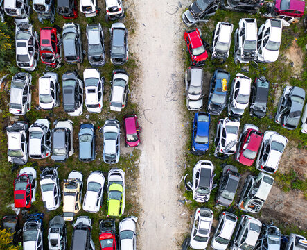Aerial view of a car junk yard with numerous wrecked and salvaged vehicles parked in organized rows on dirt ground in Petah Tikva, Center District, Israel.