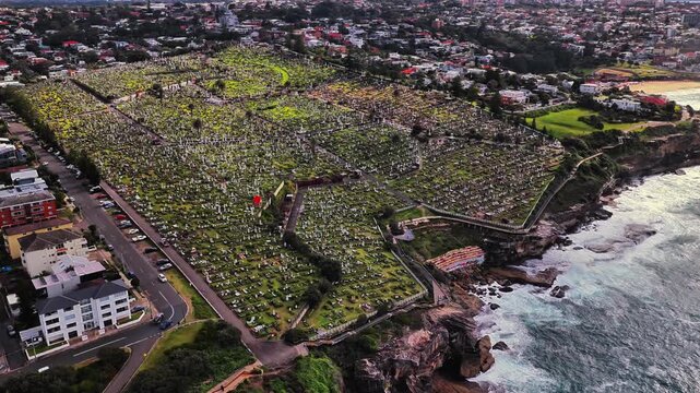 Aerial view of Waverley Cemetery on the coastal cliffs of Bronte overlooking the Pacific Ocean with historic gravestones and lush green grass in Bronte, New South Wales, Australia.
