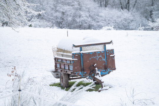 Old rusty agricultural trailer covered in deep winter snow The Concept of rural farm life and abandonment