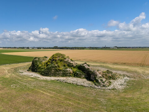 Aerial view of the Dijk van een wijf sculpture situated in a rural landscape surrounded by agricultural fields under a blue sky in Oosterbierum, Friesland, Netherlands.