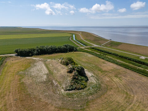 Aerial view of the Dijk van een wijf sculpture situated on a grassy dike overlooking the Wadden Sea with surrounding agricultural fields in Oosterbierum, Friesland, Netherlands.