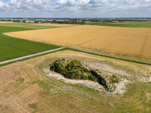 Aerial view of the Dijk van een wijf sculpture situated in a rural field surrounded by agricultural farmland under a bright sky in Oosterbierum, Friesland, Netherlands.