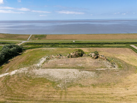 Aerial view of the Dijk van een wijf earthwork sculpture in the coastal landscape near the Wadden Sea, with grassy mounds and fields in Oosterbierum, Friesland, Netherlands.