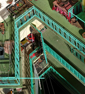 Aerial view of a residential building courtyard with turquoise metal railings, potted plants, and laundry drying racks in Belgrade, City of Belgrade, Serbia.